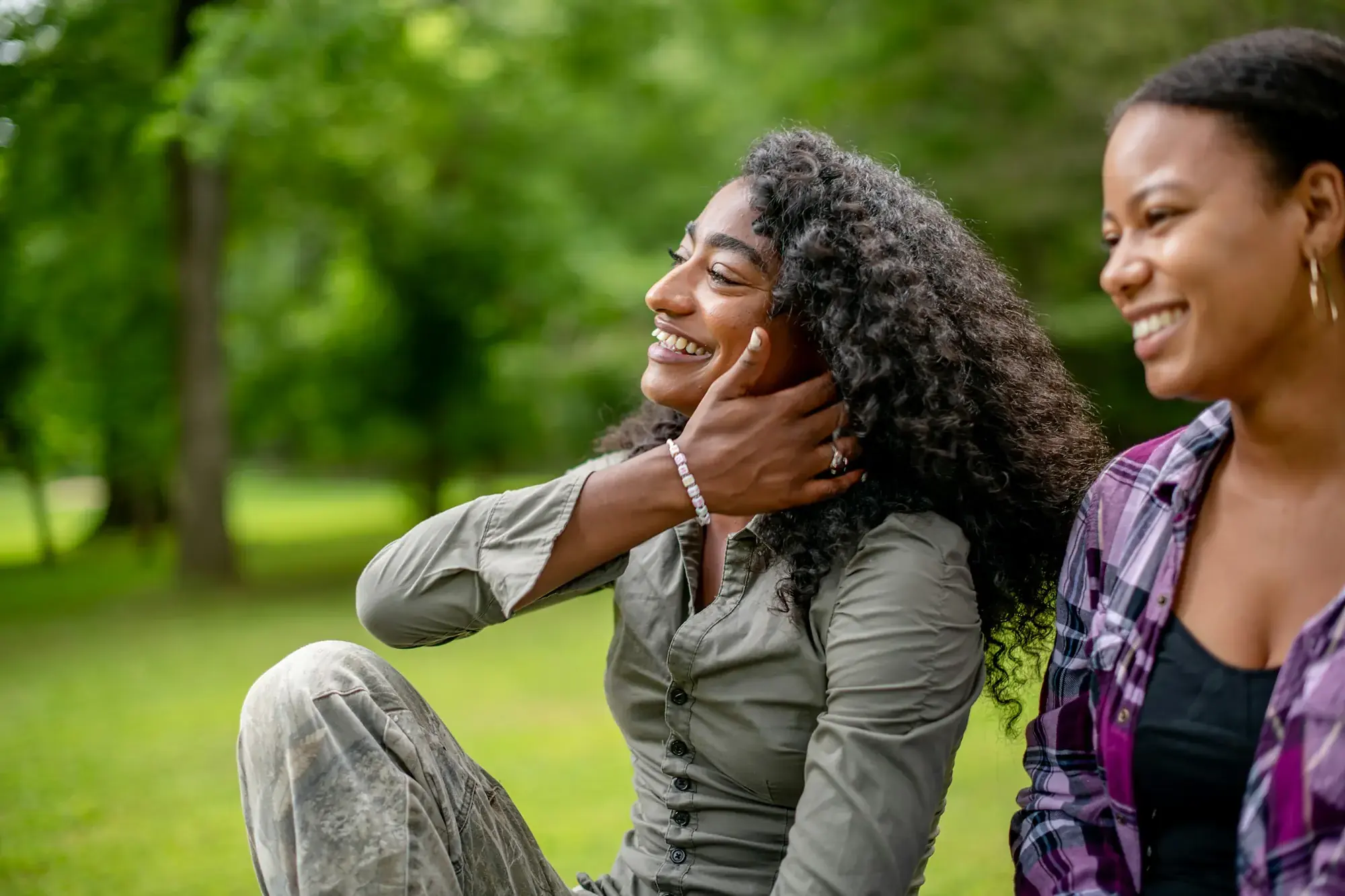 Two friends laughing together in a sunny park